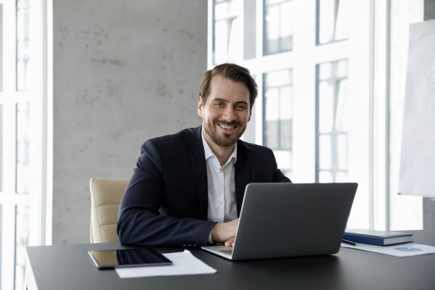 中年快乐的公司老板穿着正装在笔记本电脑前工作图片下载