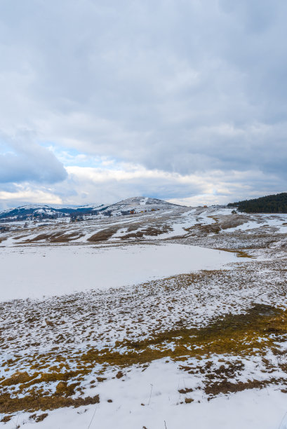 雪落在干草上。山上与多云的天空相近图片下载