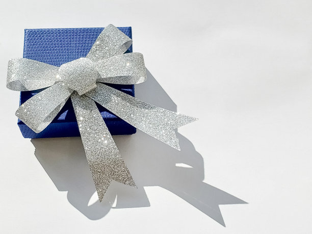 白色背景上带银色蝴蝶结的蓝色礼物，复印空间，给男人的节日礼物图片下载