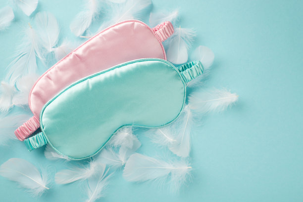 俯视图照片的两个大粉红色和蓝色丝绸蒙上许多白色轻羽毛散落在柔和的天空蓝色孤立的空背景图片下载