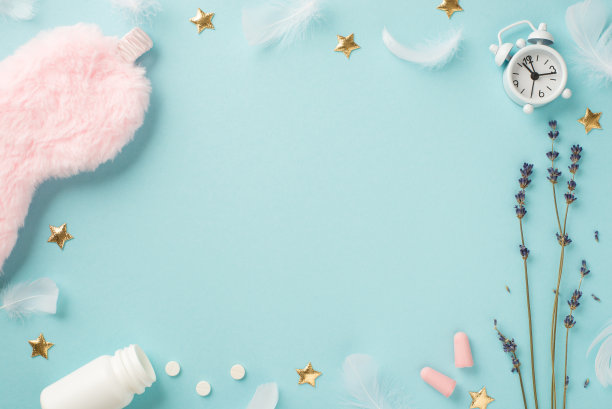 俯视图照片粉红色蓬松的睡眠面具薰衣草闹钟耳塞开瓶与药丸羽毛和金色星星在孤立的淡蓝色背景与中间的空白图片下载