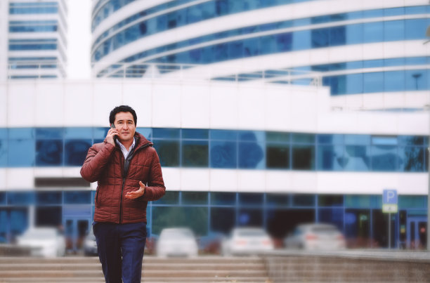 亚洲男人拿着手机走在街上。图片下载