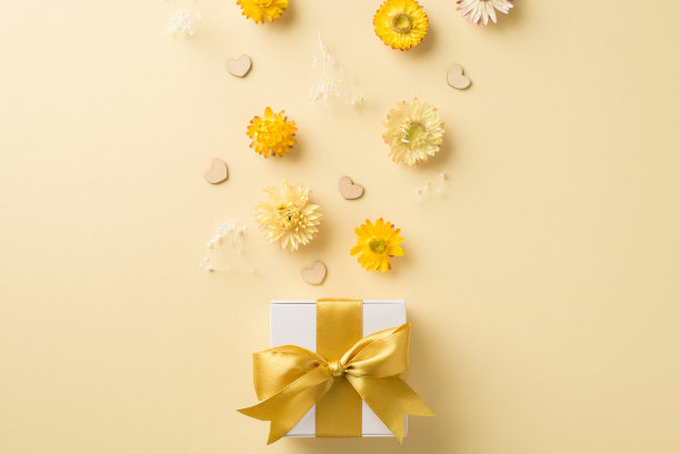 俯视图照片的女人的一天构成白色礼品盒黄色弓心和田野花在孤立的米色背景与copyspace图片下载