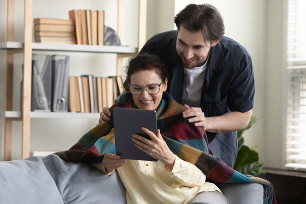 快乐的老妇人用平板电脑，花时间照顾儿子。图片下载