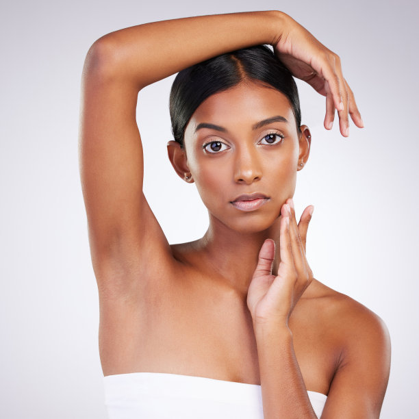 一个迷人的年轻女子在灰色背景下摆姿势的工作室肖像图片下载