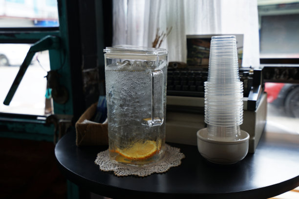 木制自助服务亭，站立的桌子装满了新鲜的泉水和塑料一次性杯子图片下载