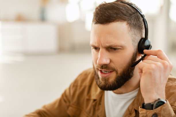 男性热线接线员在室内戴耳机的侧面照片图片下载