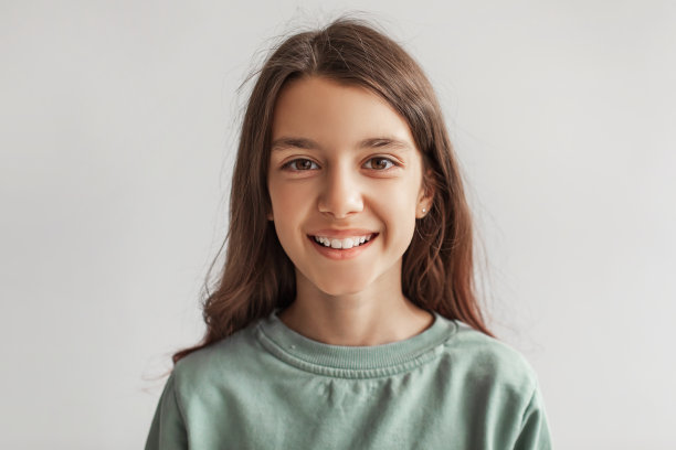 快乐女孩的头像微笑着看着相机，灰色的背景图片下载