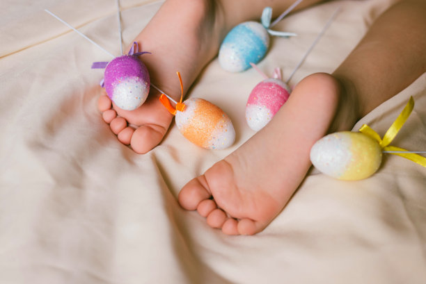 孩子们的脚和脚跟放在白色的床上迎接复活节。婴儿正在他的婴儿床上睡觉。睡眠对婴儿的重要性。睡眠模式婴儿3岁。图片下载