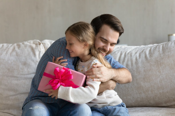 快乐的小男孩正从父亲那里得到礼物。图片下载