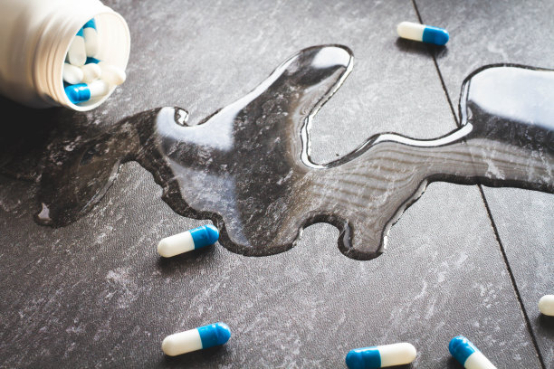 平板电脑。从手上滴下药丸和一杯水。图片下载