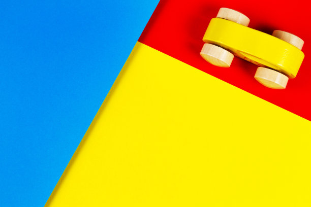 木制黄色玩具车与彩色块几何黄色蓝色红色背景。俯视图图片下载