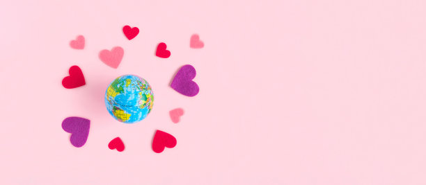 全球情人节概念-旋转地球与心脏，孤立在粉红色粉彩背景。热爱地球星球。地球模型，红色的心。俯视图，平面，复制空间。模拟。图片下载