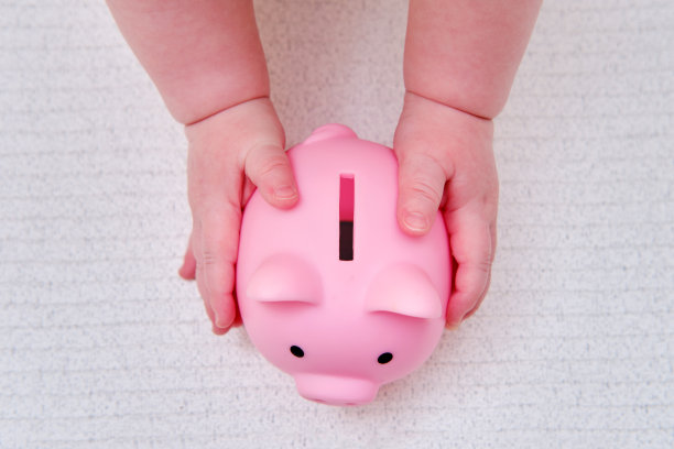 婴儿手和粉色储蓄罐，特写镜头。孩子的手指和白色背景上的物体图片下载