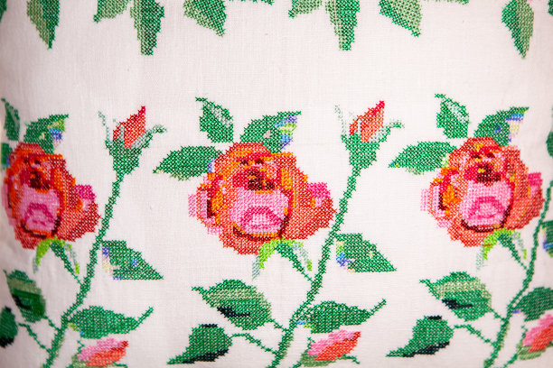 十字绣在白色亚麻枕头上玫瑰的形式，特写。刺绣设计。隔离。图片下载