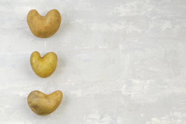 灰色背景上丑陋的心形土豆。蔬菜或食物浪费的有趣概念。前视图。副本的空间。图片下载