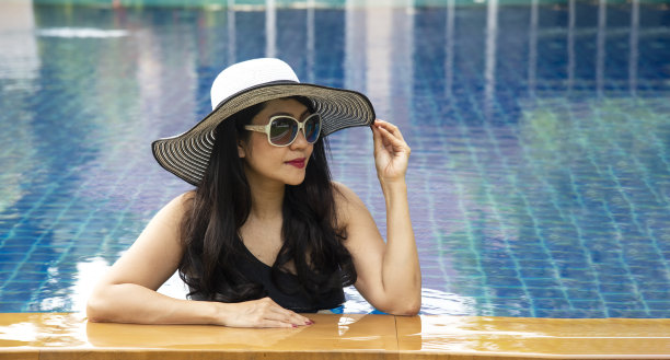 美丽的年轻亚洲妇女放松微笑周围的户外游泳池在酒店度假胜地近海海滩海洋图片下载