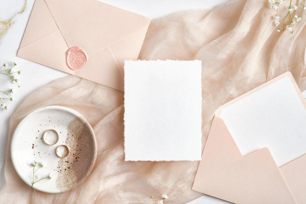 婚礼请柬模型，婚礼信封，米色布上的戒指。平躺，俯视图。图片下载
