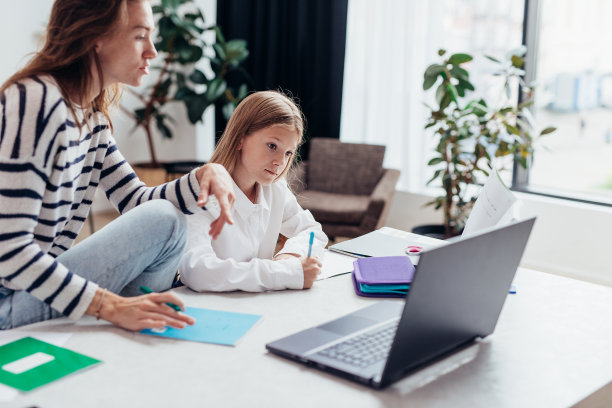 女孩做她的家庭作业，她的妈妈坐在她旁边图片下载