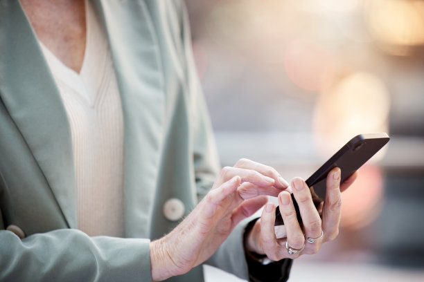 剪裁拍摄的一个不知名的女商人站在城市和使用她的手机图片下载