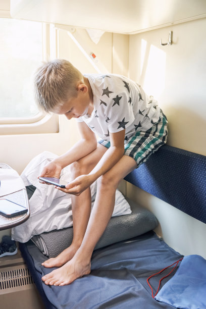 男孩坐在床靠背上用智能手机看电影图片下载