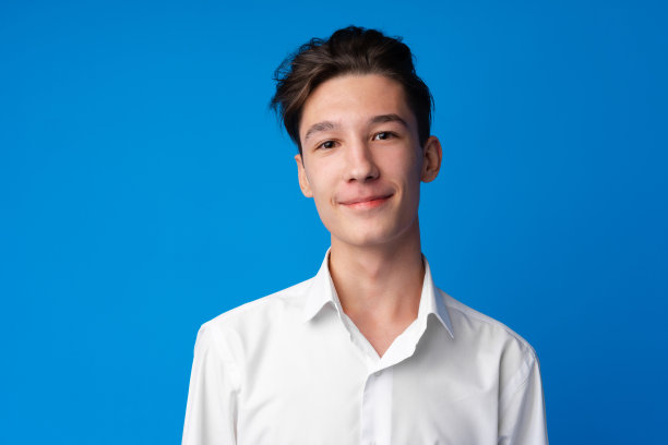 一个微笑的少年在蓝色背景下的肖像图片下载