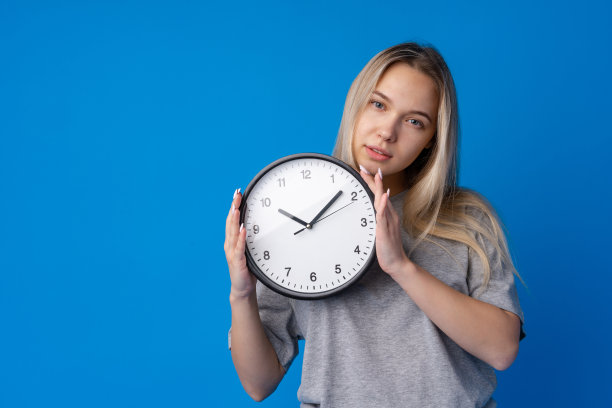美丽的少女拿着蓝色背景的挂钟图片下载