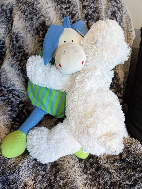 两个孩子的软玩具在沙发上的一个白熊和一个有趣的驴子之间拥抱的照片图片下载