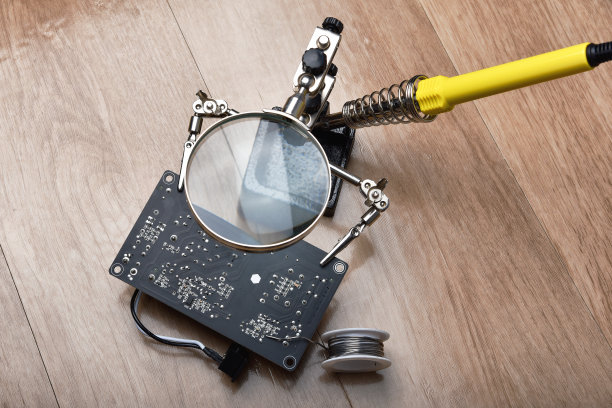 电子维修服务，技术员用烙铁和锡固定电子线路板，放大镜在焊锡架上。图片下载