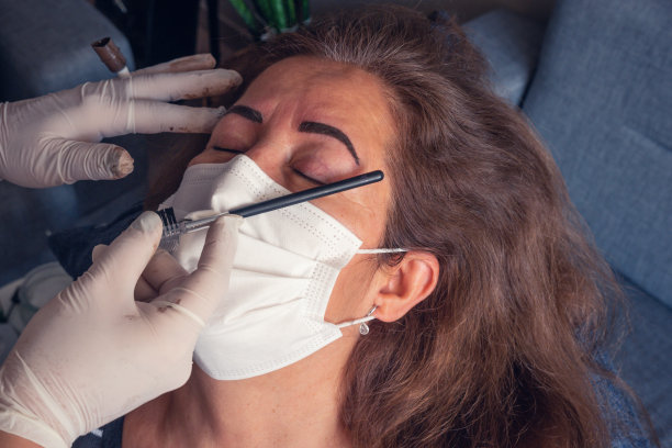 一位上了年纪的白人妇女正在给她的眉毛上永久化妆图片下载