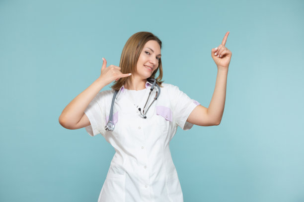 一位女医生在蓝色的背景上展示了一个电话的符号，并用手指出广告的方法或电话号码。复制粘贴。医疗保健的概念图片下载