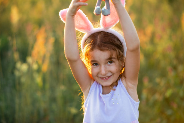 可爱的5岁小女孩，长着兔耳朵，温柔地抱着一只玩具兔子。复活节，复活节兔子，童年，快乐的孩子，春天。图片下载