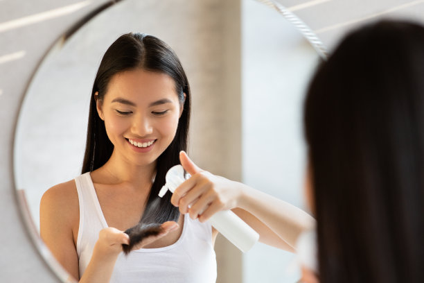 使用发胶的快乐的年轻长发韩国女人素材图片