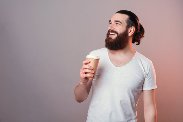 快乐的小胡子嬉皮士喝着咖啡，面带微笑图片下载