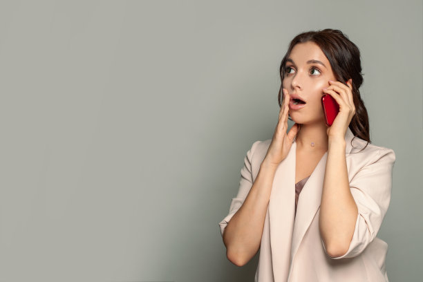 震惊的女人电话在灰色的工作室背景图片下载