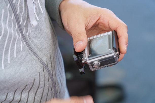 一名男子拿着他的手，看着动作摄像机上的镜头图片下载