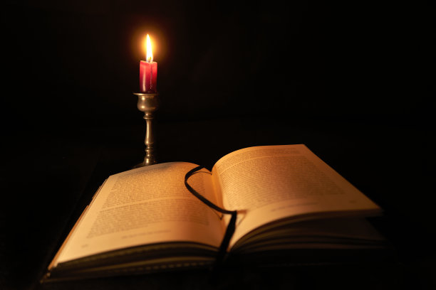 打开的书与德国文本照明的短蜡烛在一个锡制的立场图片下载