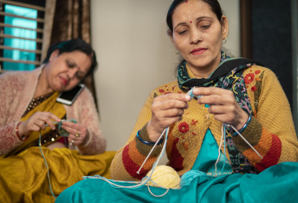 两个快乐的印度女人在家里一起织毛衣闲聊。图片下载