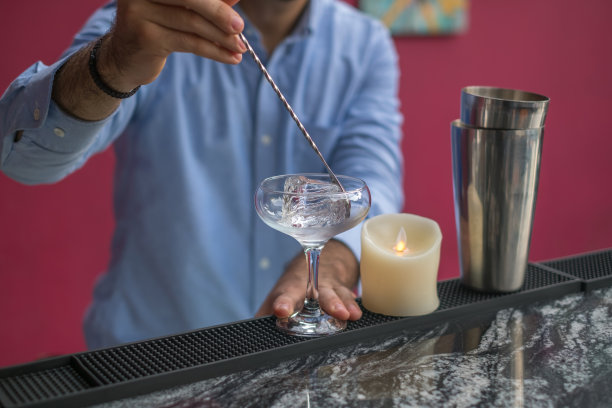 调酒师在调鸡尾酒前用冰块冷却杯子。近距离的照片图片下载