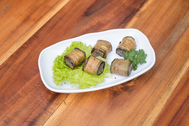 用新鲜生菜和欧芹装饰的茄子卷放在白色盘子里图片下载
