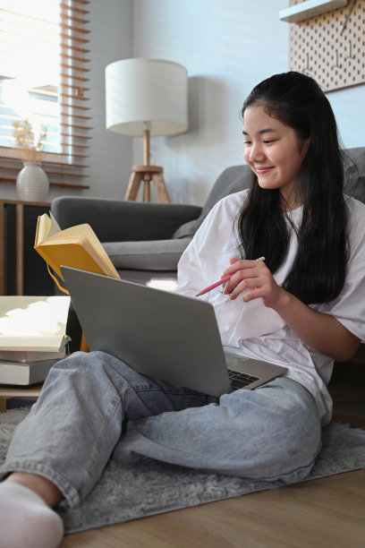 可爱的亚洲女孩坐在地板客厅和上网笔记本电脑。图片下载