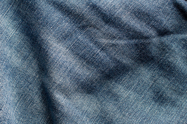 蓝色牛仔裤的质感，波浪和阴影。俯视图和近视图照片。图片下载