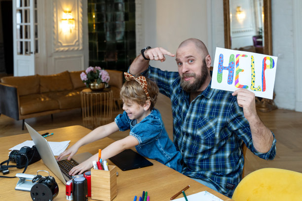 父亲带着孩子在家用笔记本电脑远程工作。图片下载