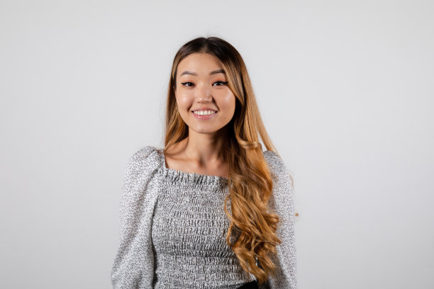 微笑的金发亚洲女孩与卷曲的头发在白色的背景图片下载