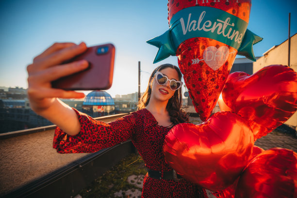 一个漂亮的女人拿着氦气球在自拍图片下载