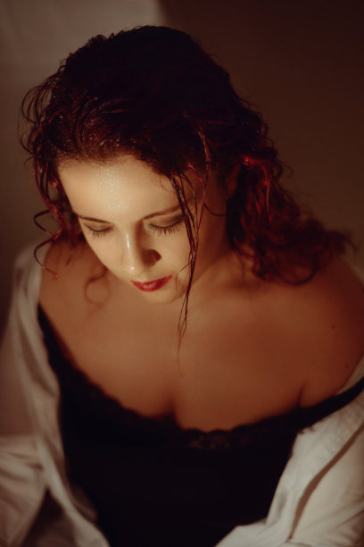 红发年轻和美丽的女人与湿头发摆姿势，而向下看图片下载