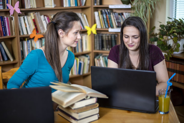 两个漂亮的学生在图书馆学习。图片下载