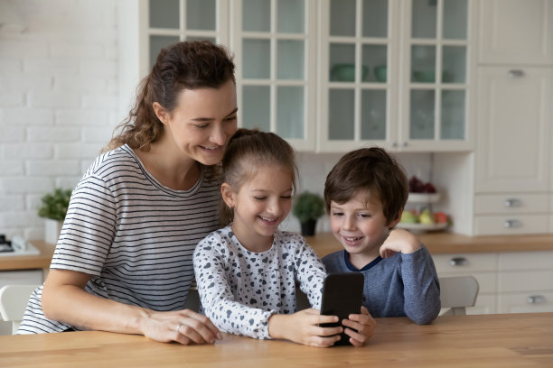 快乐的有爱心的母亲用手机和小孩在一起。图片下载