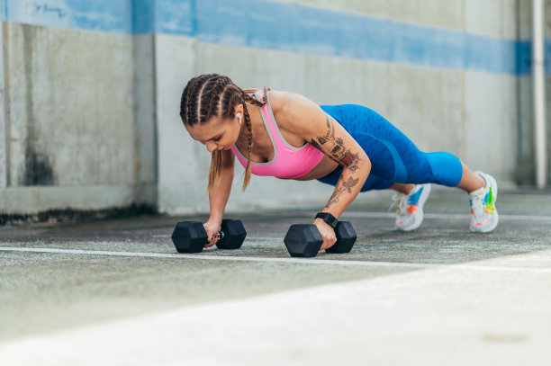 女子在户外训练时使用哑铃和耳机图片下载