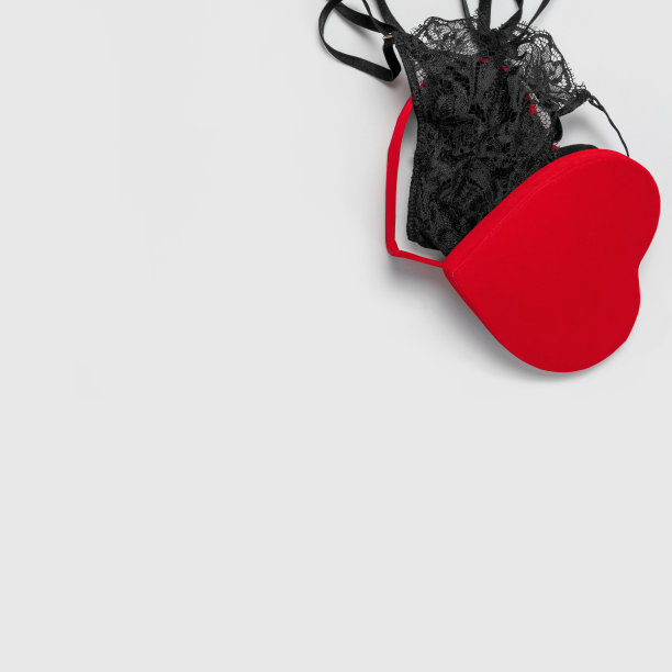 蕾丝性感黑色女性内衣在红色礼品盒形式的心灰色背景平躺顶视图。黑色蕾丝内衣。时尚的概念。女人的胸罩，内裤，的衣服。爱的节日礼物图片下载